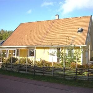 Gukt hus med rött tegeltak och en gärdesgård runt huset.