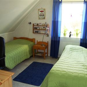 Two single beds with green bedspread and blue curtains. 