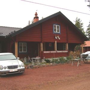 Exteriör av rödmålat hus med stor veranda.