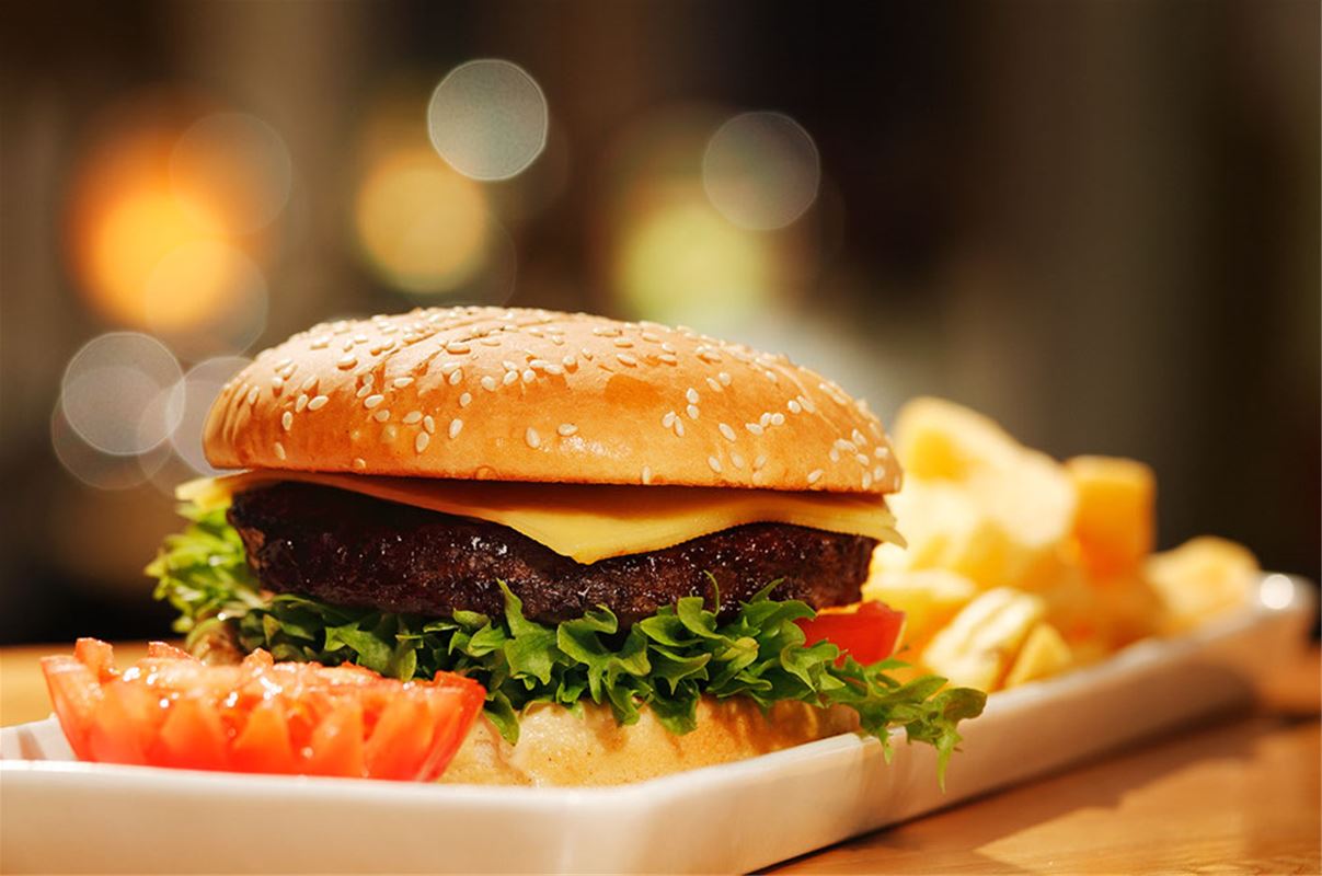 Hamburger on plate with french fries around.