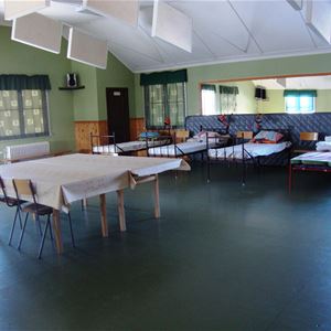 Beds in a big dormitory with a table in the middle.