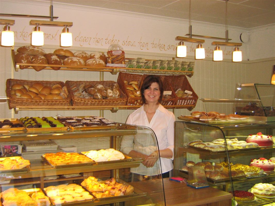 Staff behind the counter with various pastries and cakes.