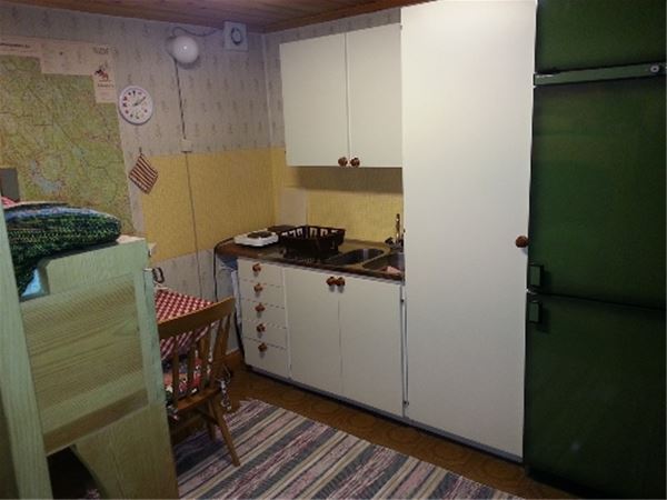 White kitchenette with stove, sink and a green fridge and freezer. 