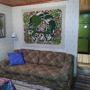 Brun-rutig soffa med en färgglad, grön väggbonad ovanför.