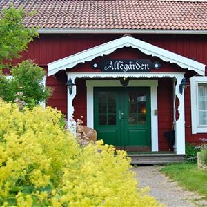 The entrance of Allégården with a green door in teh red building with white linings and windows.