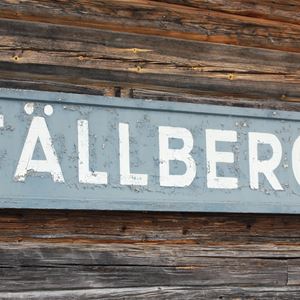 Skylt med namnet Tällberg sitter på en brun timmervägg. 