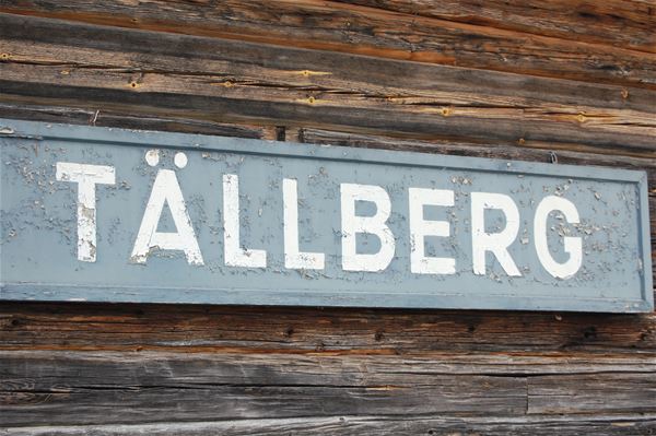 Skylt med namnet Tällberg sitter på en brun timmervägg.  