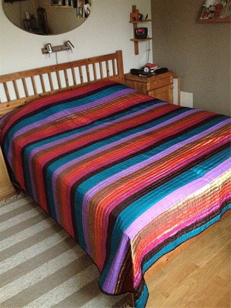 Colorful bedspread on a double bed. 