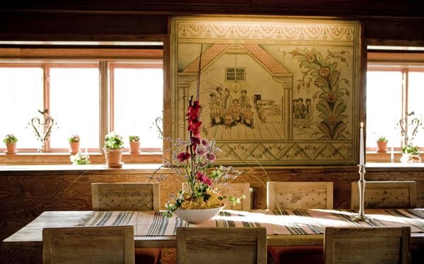 Långbord med dala stolar i salong med traditionell kurbits målning på väggen.  