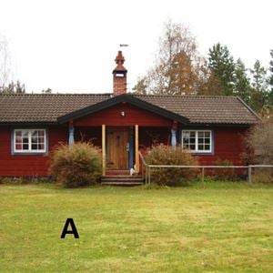 Exterior of redpainted cottage with a veranda.