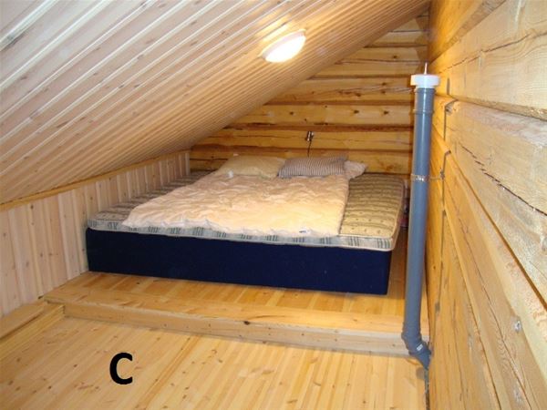 Stor madrass på golvet i rum med lutande tak på loftet. 