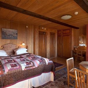 Double bed in a room with pine walls, floor and ceiling. 