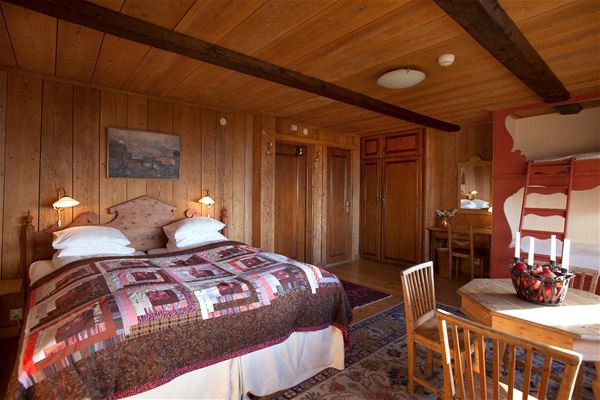 Double bed in a room with pine walls, floor and ceiling.  