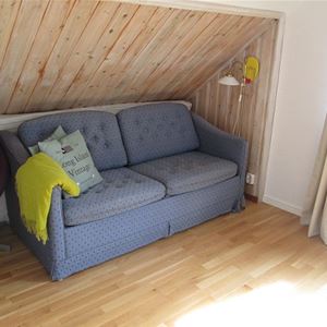 Grey sofa placed under a sloping roof of pine.