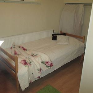 Single bed in a wooden fram and a white bedspread. 