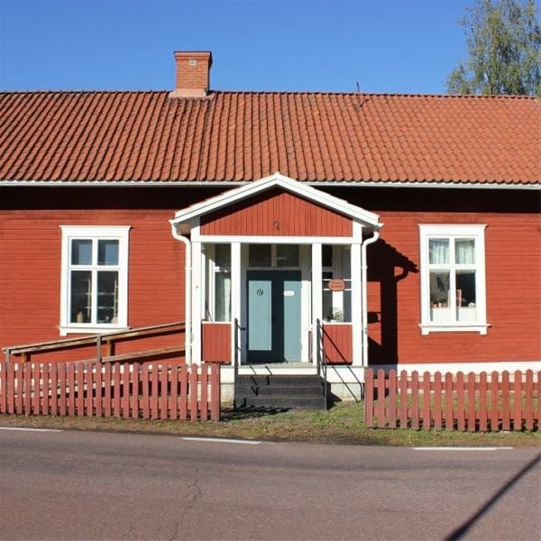 Rödmålat hus med vita foder och blå dörr.  