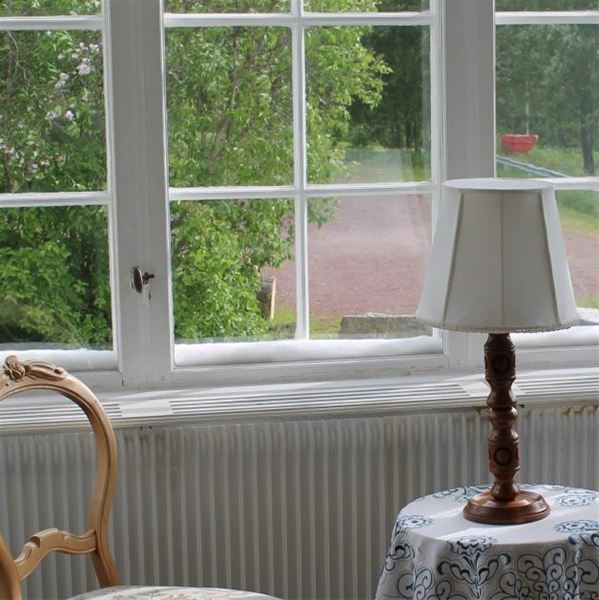 Detalj på spröjsade fönster, litet bord med lampa.  