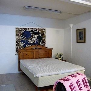 Dubbelsäng med sänggavel i snidat trä och en stor blåmönstrad tavla ovanför.