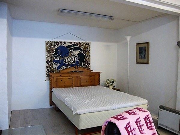 Dubbelsäng med sänggavel i snidat trä och en stor blåmönstrad tavla ovanför. 
