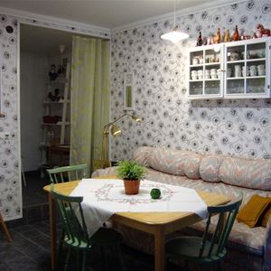 Soffa med litet vitrinskåp ovanför och ett matbord med stolar framför. 