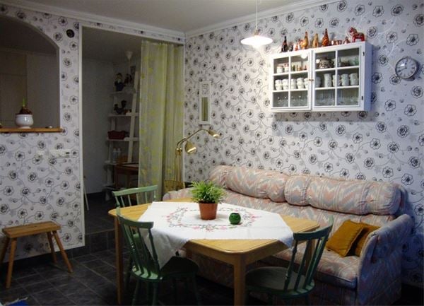 Soffa med litet vitrinskåp ovanför och ett matbord med stolar framför.  