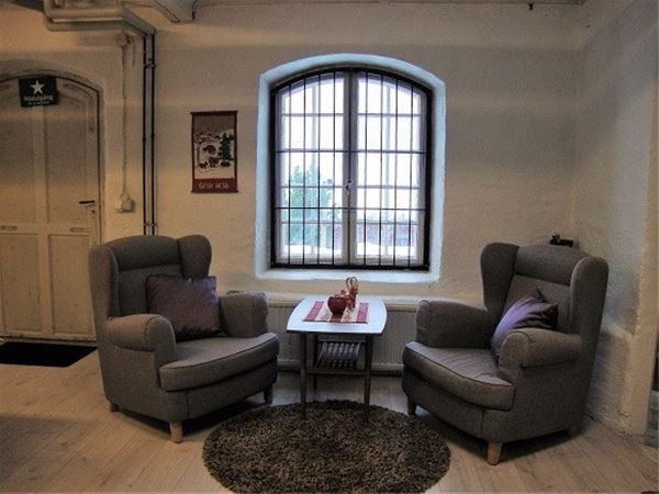 Two grey armchairs and a small table between in front of a barred window. 
