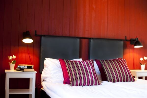 hotellrum, röd vägg, svart sänggavel, röda kuddar. 