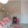 Enkelsäng med lapptäcke i rosa och vitt, en liten rosa barnstol och rosa fjärilar på en grå vägg.