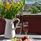 Fruktfat, två vinglas och blommor i en kanna står på ett balkongbord med utsikt över Siljan. 