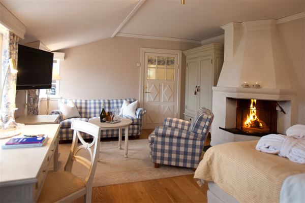 A suite with a double bed and a fire place. 