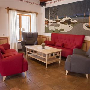 Group with red sofas and grey armchairs around a small table. 