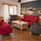 Röda soffor och gråa fåtöljer runt ett soffbord i ett stort rum. 