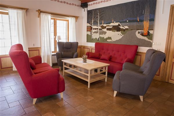 Röda soffor och gråa fåtöljer runt ett soffbord i ett stort rum.  