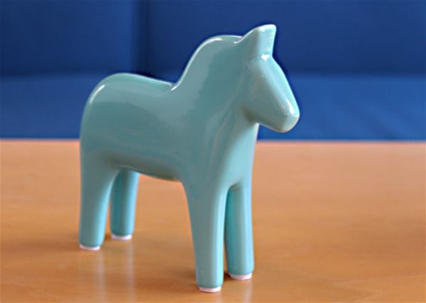 Ljusblå dalahäst på ett bord. 