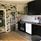 Kitchen with black cupboards and patterned wallpaper in black, grey and white.