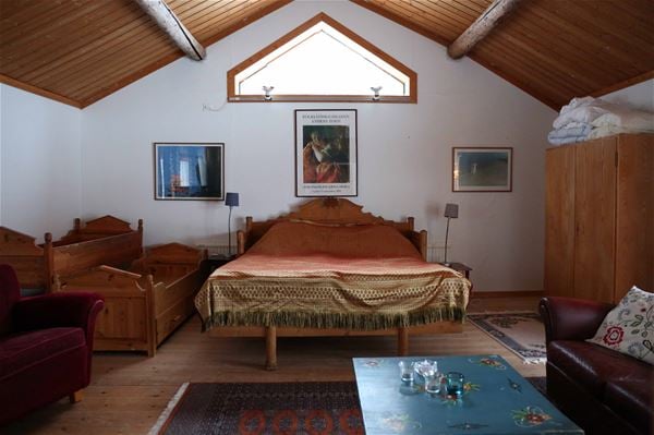 Stort sovrum med en dubbelsäng av en gammal kökssoffa, ytterligare en kökssoffa och en garderob i rummet. 