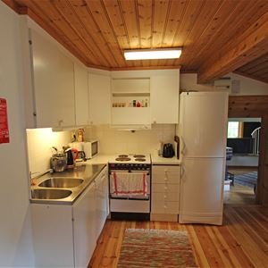 Vitt kök i ett rum med tak och golv av furu. 