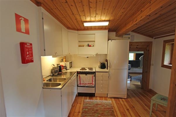 Vitt kök i ett rum med tak och golv av furu.  