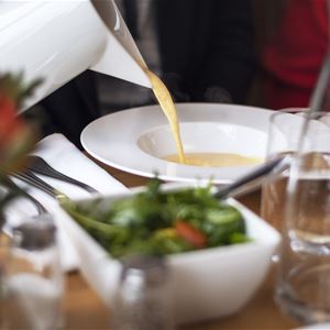 Carafe with soup poured on a plate.