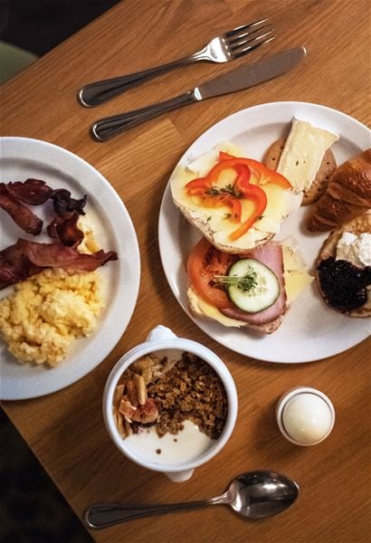 Frukost med ägg, bacon, smörgåsar och fil med müsli. 