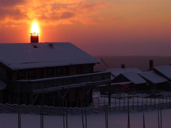 Timmerhus i solnedgång en vinterdag. 