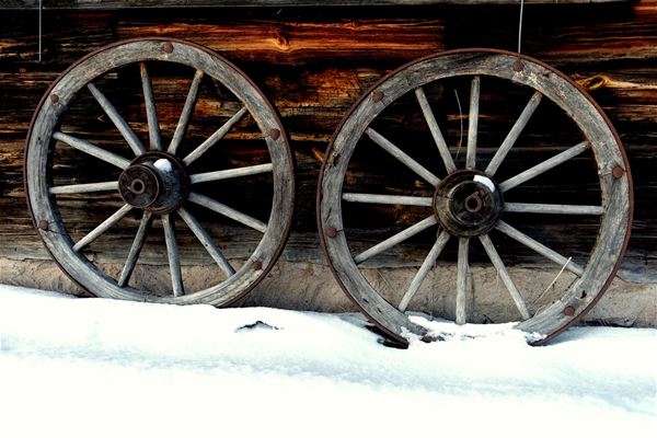 Detaljbild på två hjul i trä mot en timmervägg.  