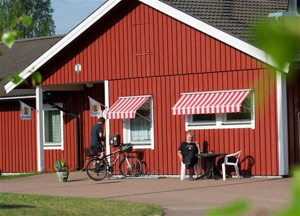 Exterior of the hostel with red wooden panel and white linings.  
