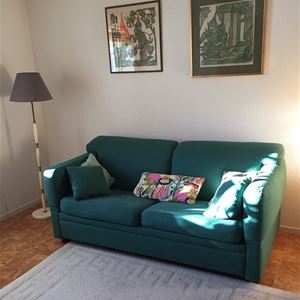 Grön soffa med golvlampa bredvid.