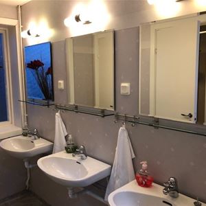 Sanitetsrum med tre tvättställ och speglar. 