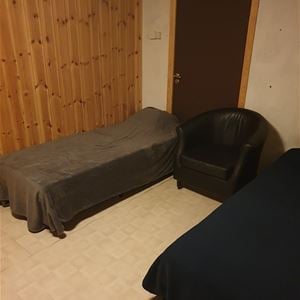 Room with two beds and an arm chair.