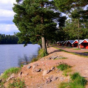 Röda camping stugor längs vattnet.