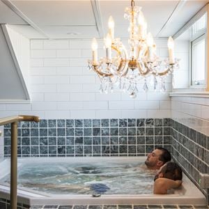 Two men in a jacuzzi with a crystal chandelier in the roof. 