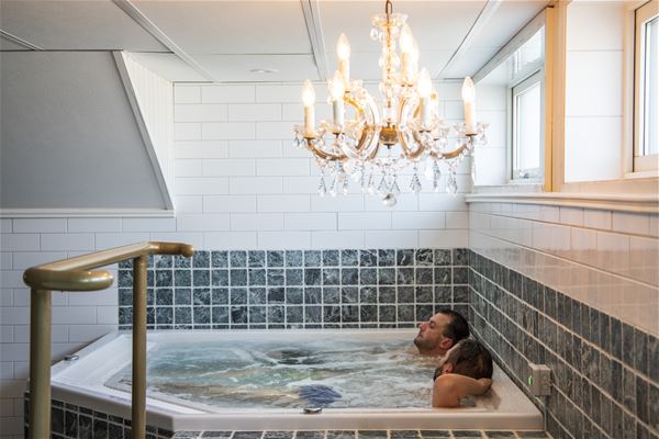 Two men in a jacuzzi with a crystal chandelier in the roof.  