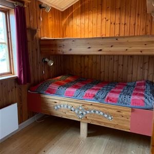 Bunkbed with painted details and a grey and red bedspread.